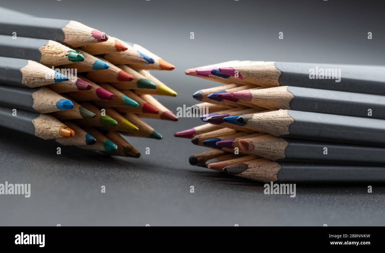 Image de clôture de deux jeux opposés de crayons de couleur sur fond gris Banque D'Images