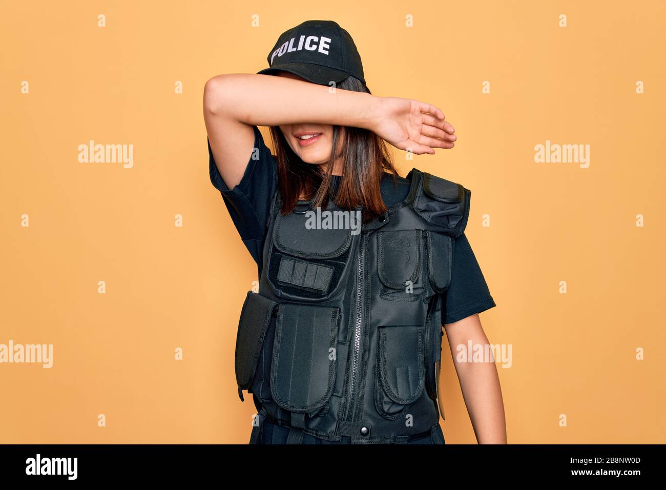 Jeune policier brunette portant uniforme de police BULLETProof et casquette  couvrant les yeux avec bras souriant gai et drôle. Concept aveugle Photo  Stock - Alamy
