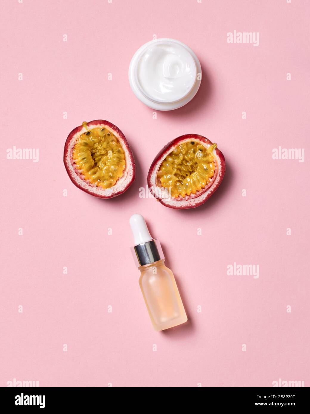 Soins de beauté. Crème acide hyaluronique et fruits de la passion coupés en deux isolés sur le rose Banque D'Images