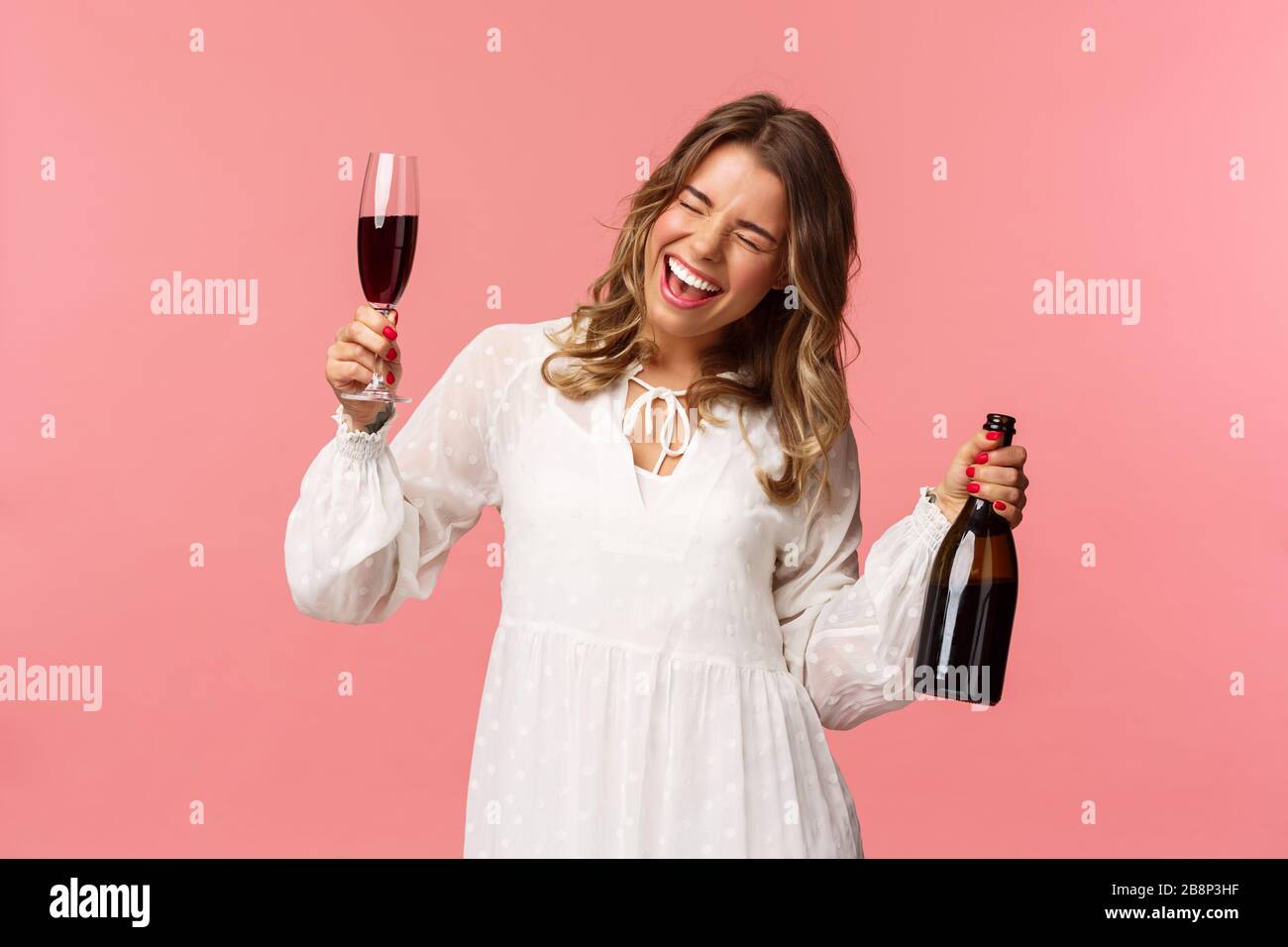 Vacances, printemps et concept de fête. Portrait d'une jeune fille blonde excitée et émotive qui danse et fête, s'amusant à dire oui chanter Banque D'Images