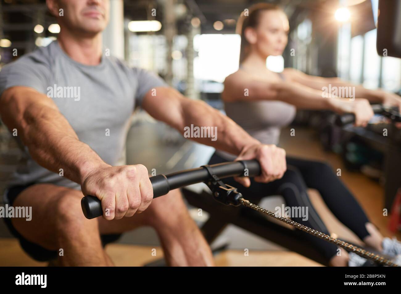 Image rognée d'un homme musculaire utilisant une machine d'exercice pendant l'entraînement de force dans une salle de sport moderne, espace de copie Banque D'Images