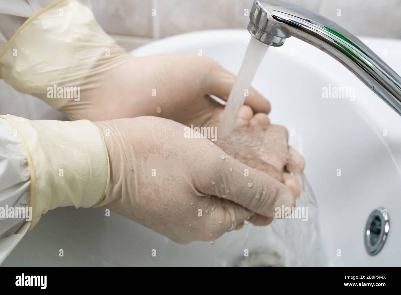 Le chirurgien lave et traite les mains avec des gants en caoutchouc blanc. Désinfection médicale. Banque D'Images