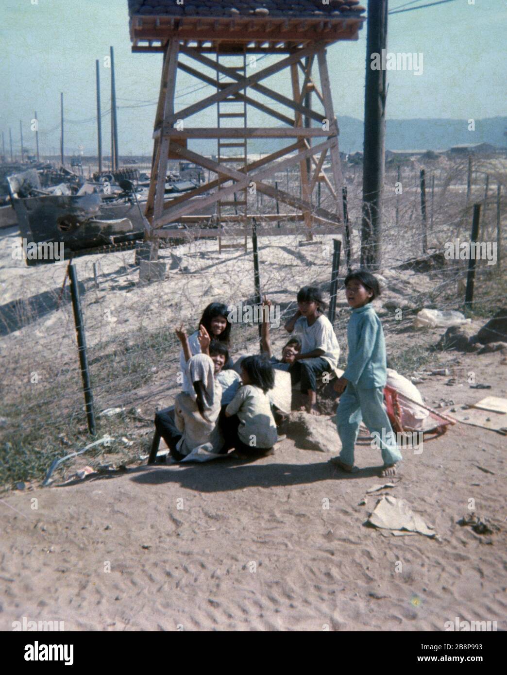 1968, Danang, Vietnam des enfants vietnamiens pendaient autour de l'aéroport de Danang pendant la guerre avec une tour de guet et un sac de sable en arrière-plan. Banque D'Images