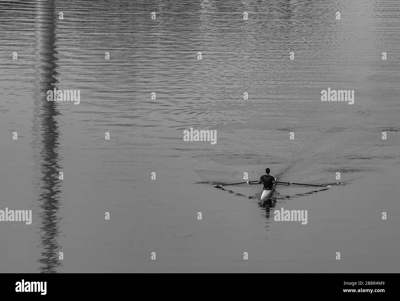 Inconnu homme ramer un canoë le matin près du lac.vue de loin. Banque D'Images