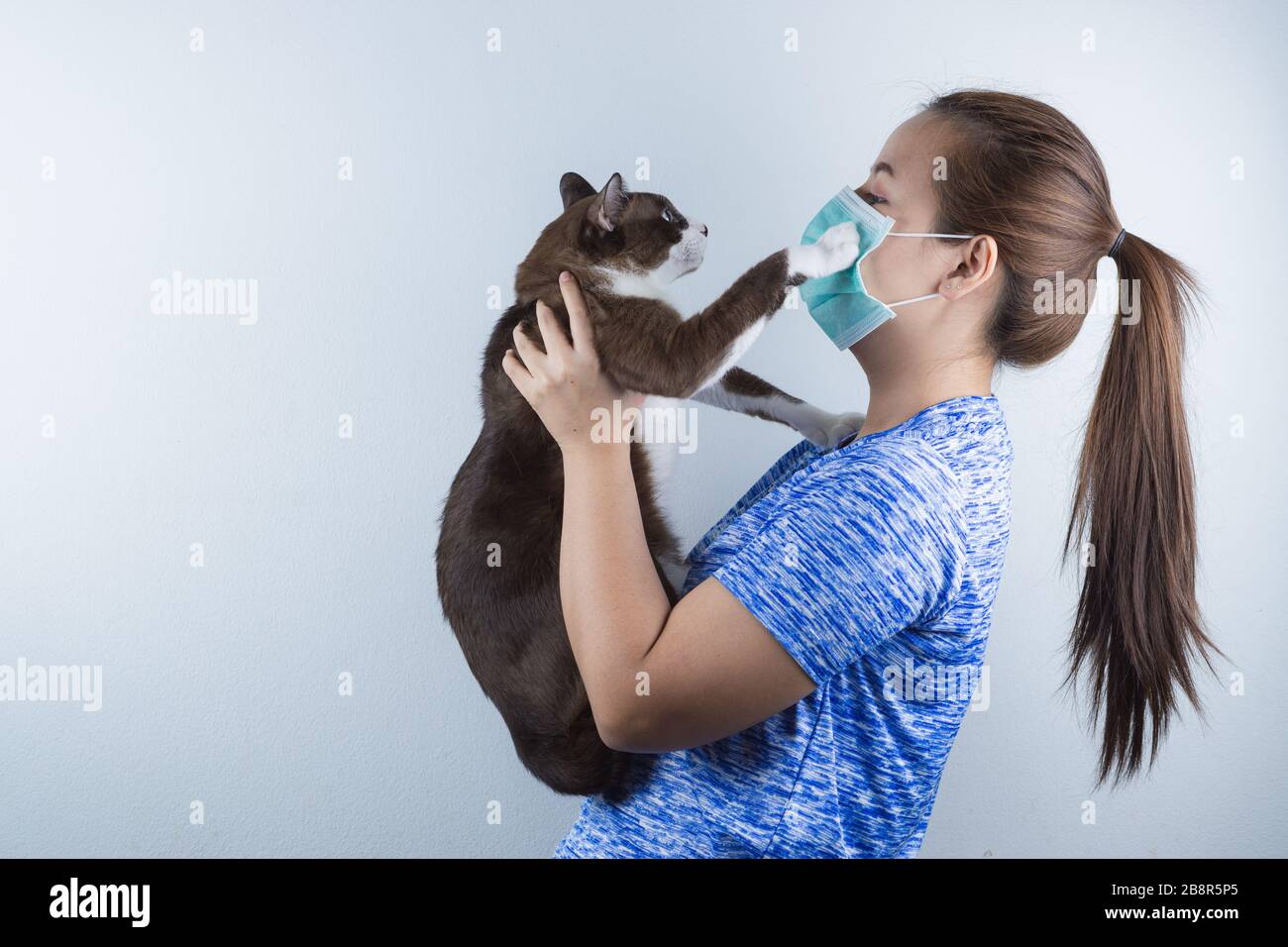 Une fille portant un masque pour protéger le coronavirus, pm 2.5 et allergique à la fourrure de chat. Coronavirus et pollution atmosphérique PM 2.5 concept. Banque D'Images