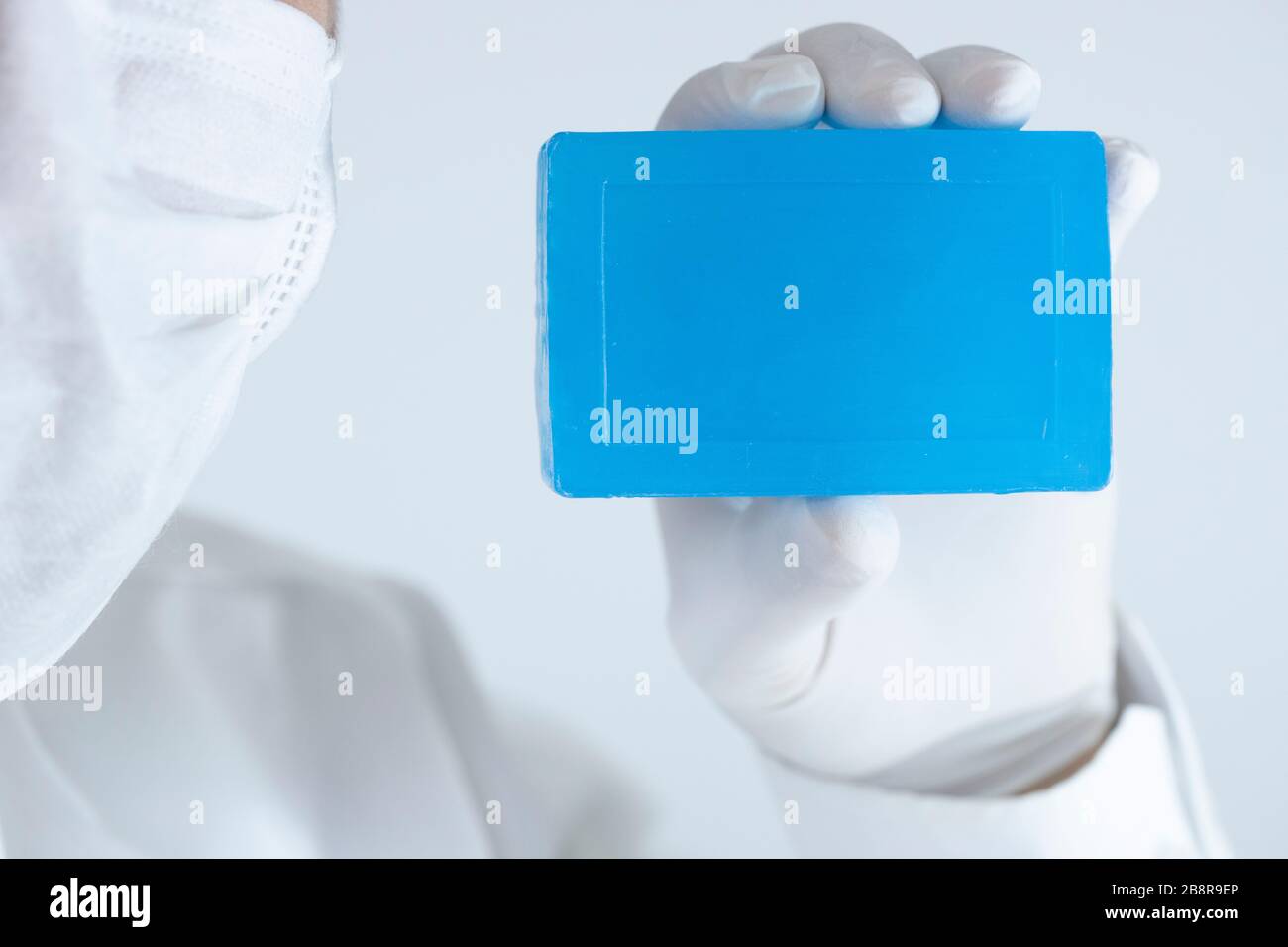 Savon pour le nettoyage personnel contre les virus et les bactéries. Savon bleu dans une main portant des gants. Une photo a été prise en studio. Banque D'Images