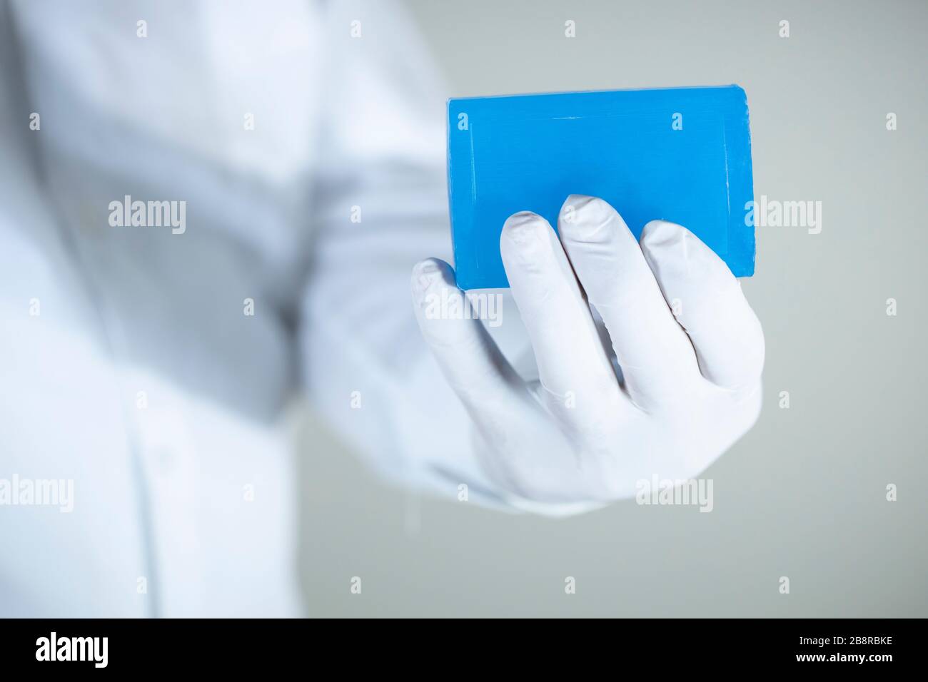 Savon pour le nettoyage personnel contre les virus et les bactéries. Savon bleu dans une main portant des gants. Une photo a été prise en studio. Banque D'Images