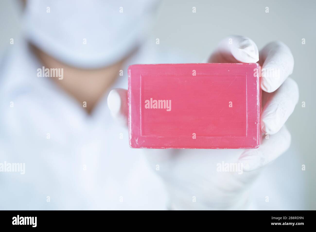 Savon pour le nettoyage personnel contre les virus et les bactéries. Savon rouge dans une main portant des gants. Une photo a été prise en studio. Banque D'Images