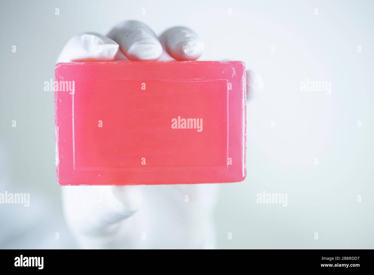 Savon pour le nettoyage personnel contre les virus et les bactéries. Savon rouge dans une main portant des gants. Une photo a été prise en studio. Banque D'Images