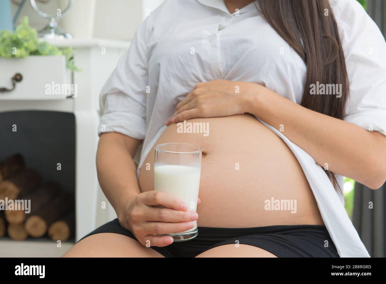 Femme enceinte tenant un verre de lait frais pour les soins de santé. Banque D'Images