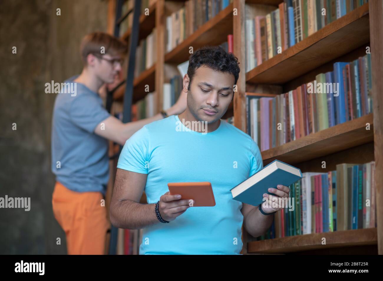 Deux amis à la recherche des livres nécessaires dans la bibliothèque Banque D'Images