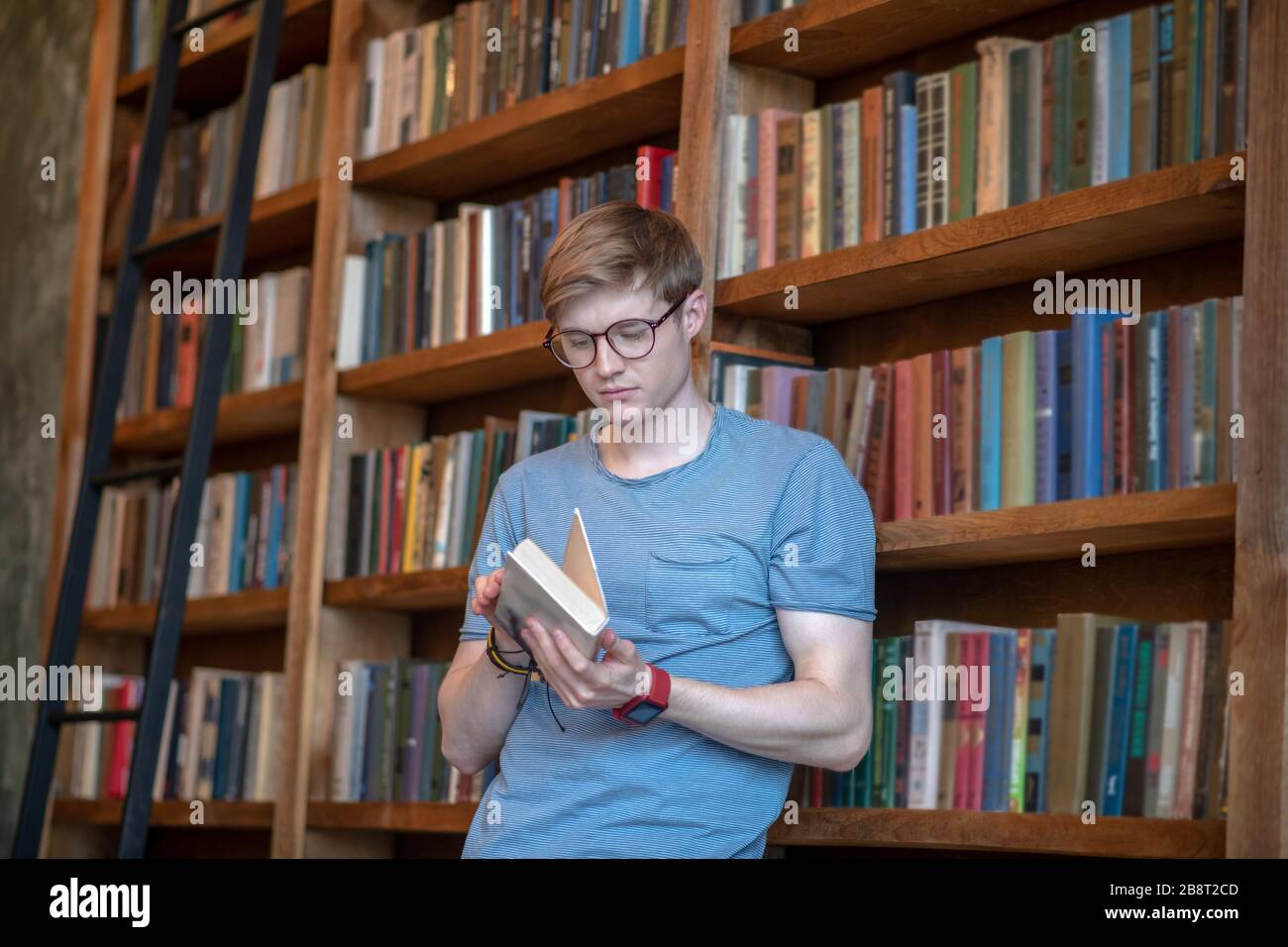 Jeune homme dans des lunettes tenant un livre Banque D'Images