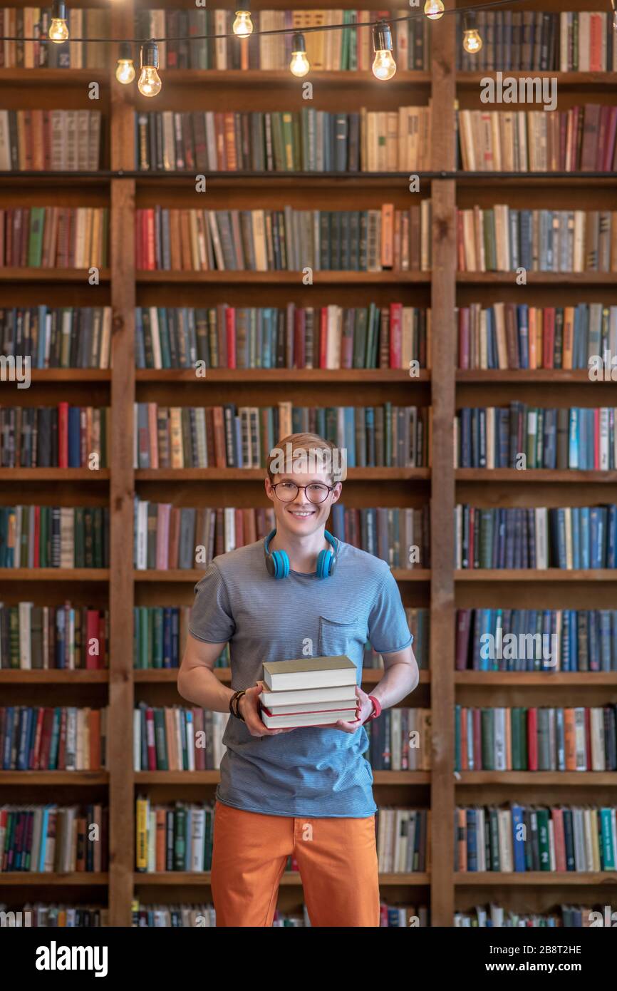 Jeune homme aux cheveux justes dans des lunettes debout dans la bibliothèque Banque D'Images