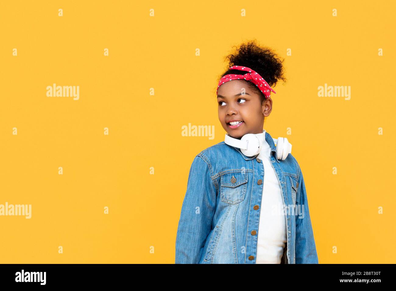 Fille africaine mélangée souriante et tendance regardant l'espace de copie de côté studio tourné isolatiné sur fond jaune coloré Banque D'Images