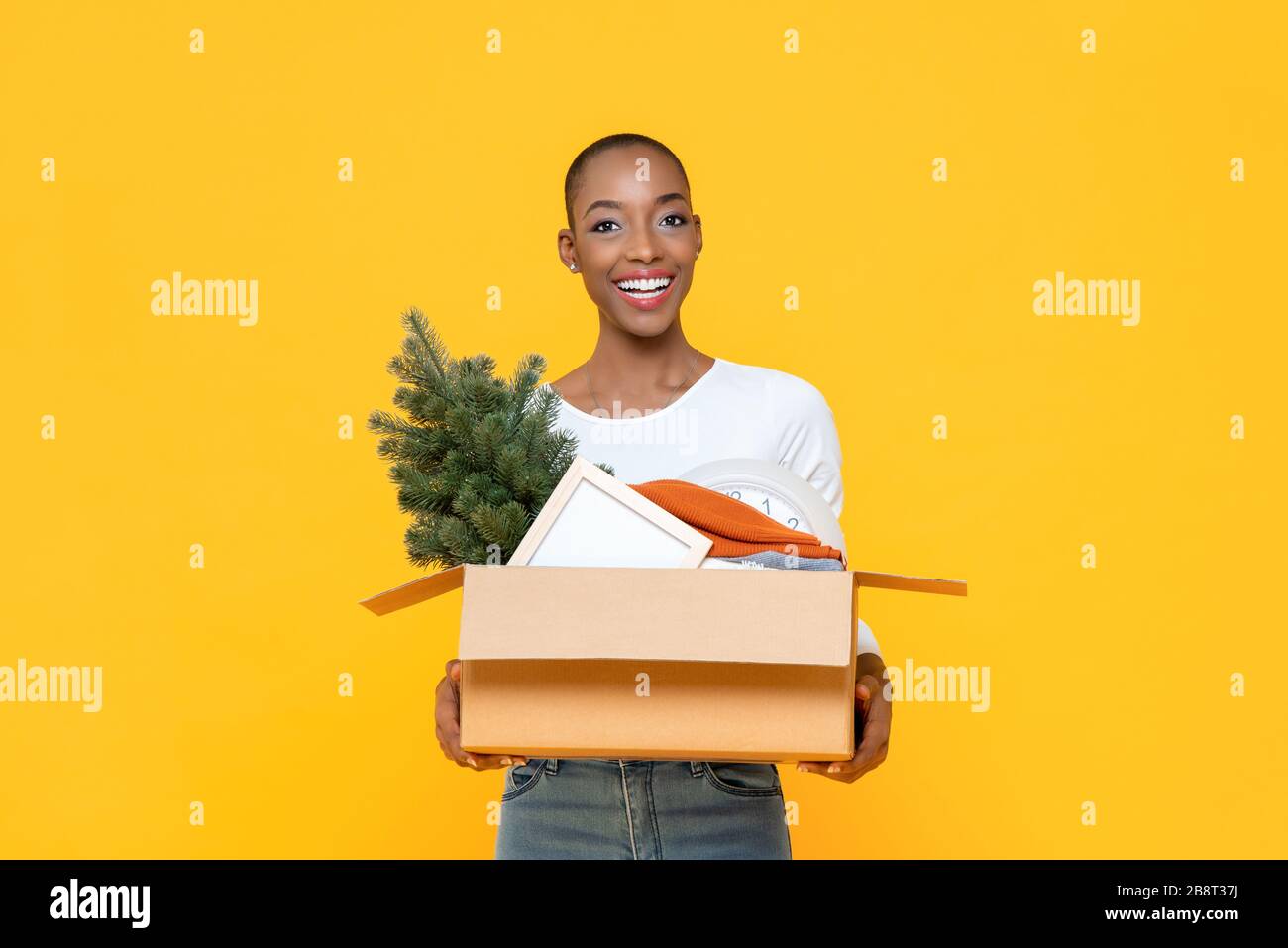Heureuse femme africaine souriante tenant boîte déplacer des choses à la nouvelle maison Banque D'Images