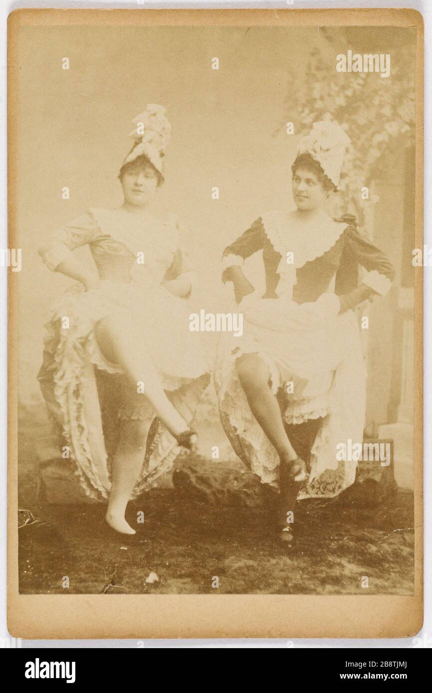 Portrait de Louise Weber (1866-1929) connue sous le nom de la Goulue cancan danseuse et réseau d'égouts (à droite). Portrait de Louise Weber (1866-1929) dite la Goulue en danseuse de french cancan et de grille d'égout (à droite). Femmes en costume de scène. Photographie anonyme pry en studio (décor PEint en trompe-l'oeil). Rage sur papier alluminé. Paris, musée Carnavalet. Banque D'Images