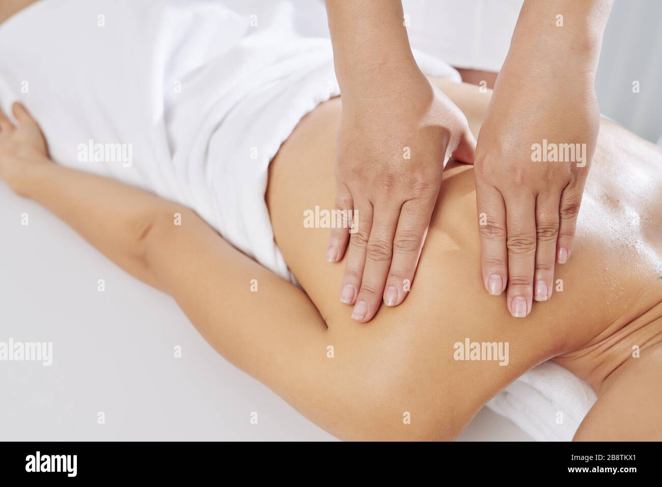 Image rapprochée du massothérapeute appliquant une pression soutenue en utilisant des traits lents et profonds pour cibler les couches intérieures des muscles Banque D'Images