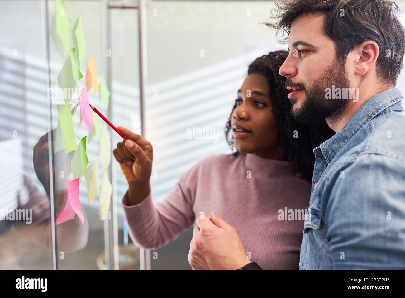 Web designer équipe créative brainstorming sur mur de verre avec des notes adhésives Banque D'Images