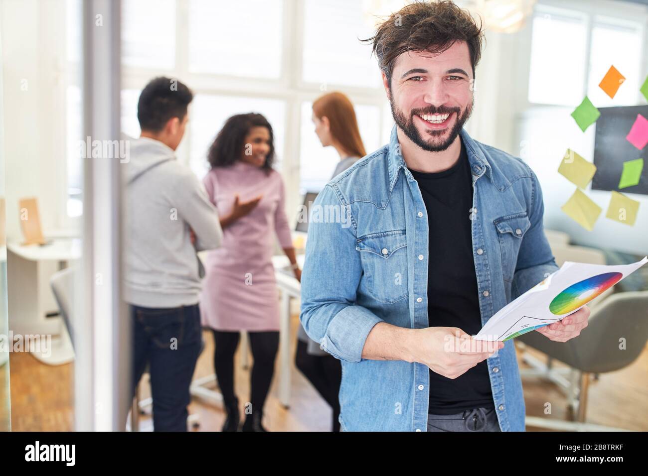 Graphiste avec roue de couleur devant l'équipe au bureau d'une agence Internet Banque D'Images