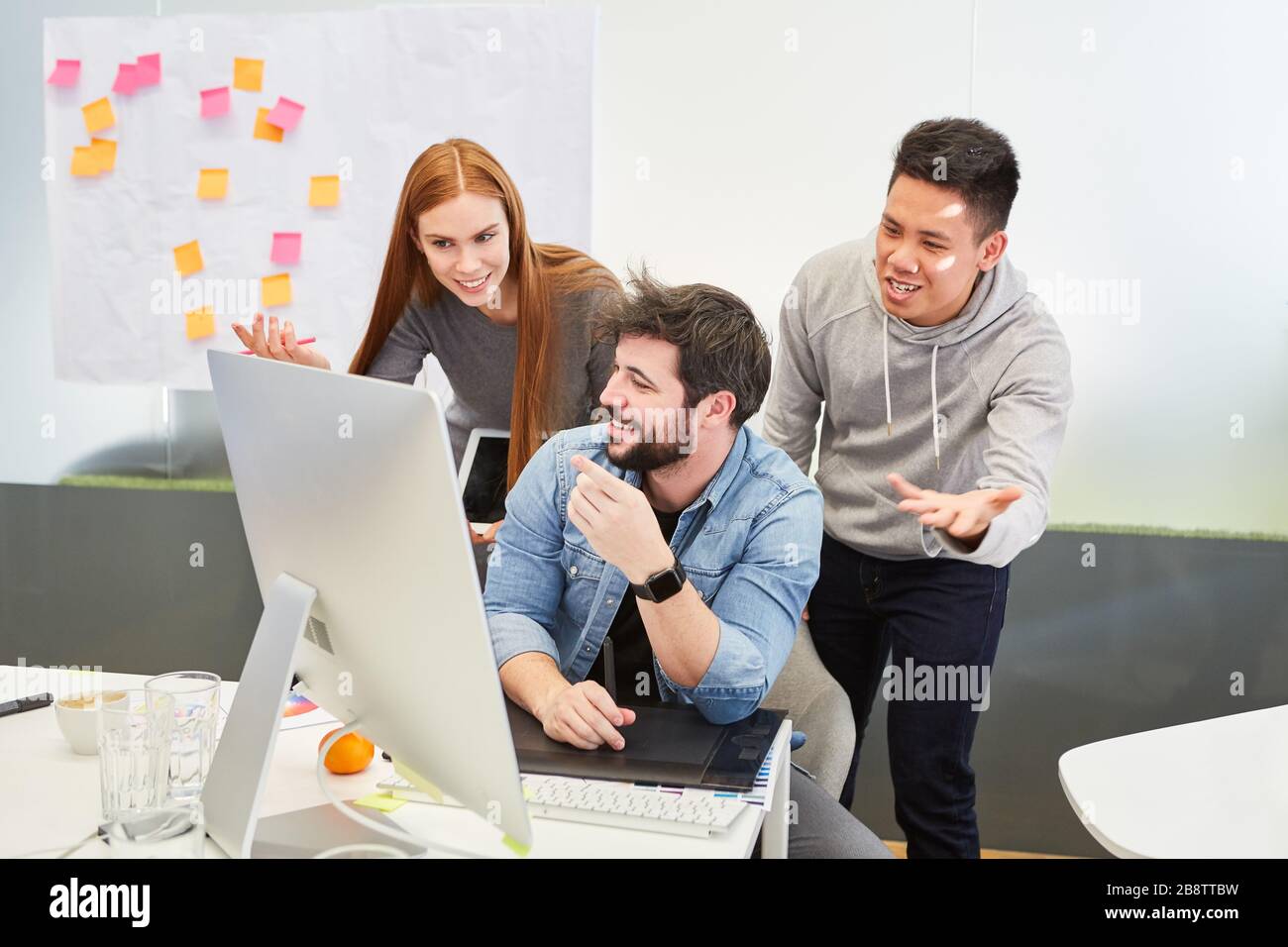 Une équipe créative dynamique sur PC encourage un développeur pendant le développement du projet Banque D'Images