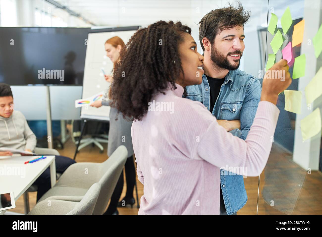 Remue-méninges de l'équipe de créateurs créatifs avec des notes adhésives sur le mur de verre Banque D'Images