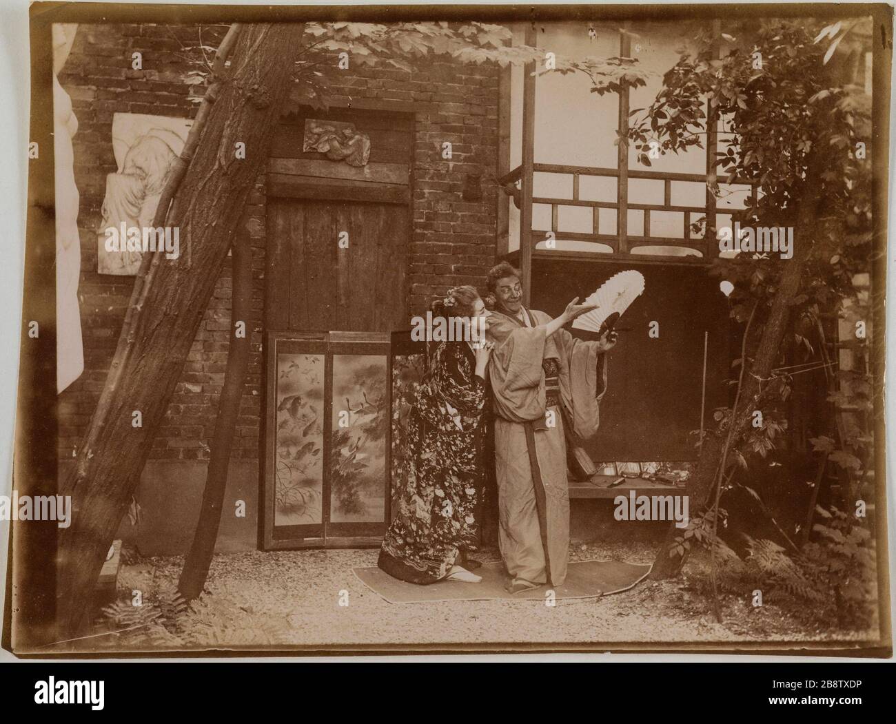 Couple d'acteurs en costume traditionnel japonais jouant le mime avec un ventilateur dans un jardin devant un écran. Couple d'acteurs en costumes traditionnels japonais jouant la pantomime avec un Eventail dans un jardin devant un paravent. Photographie anonyme, vers 1900. Paris, musée Carnavalet. Banque D'Images
