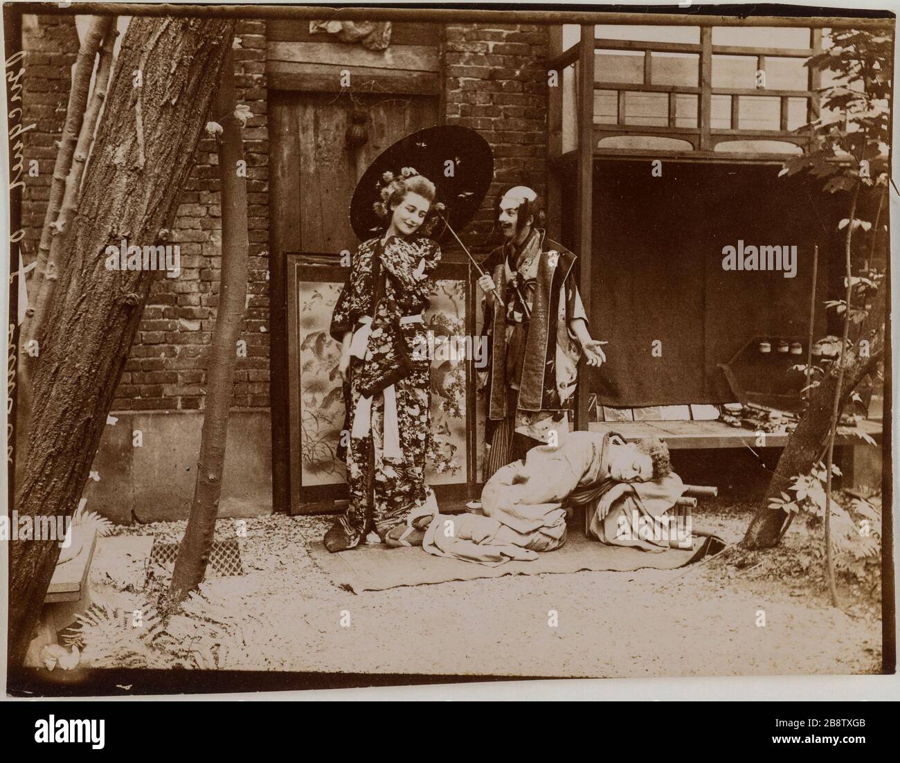 Trois acteurs portant des costumes traditionnels japonais jouant dans un jardin, jeune homme endormi au premier plan. Trois acteurs porte des costumes traditionels japonais jouant dans un jardin, jeune homme assoupi au premier plan. Photographie anonyme, vers 1900. Paris, musée Carnavalet. Banque D'Images