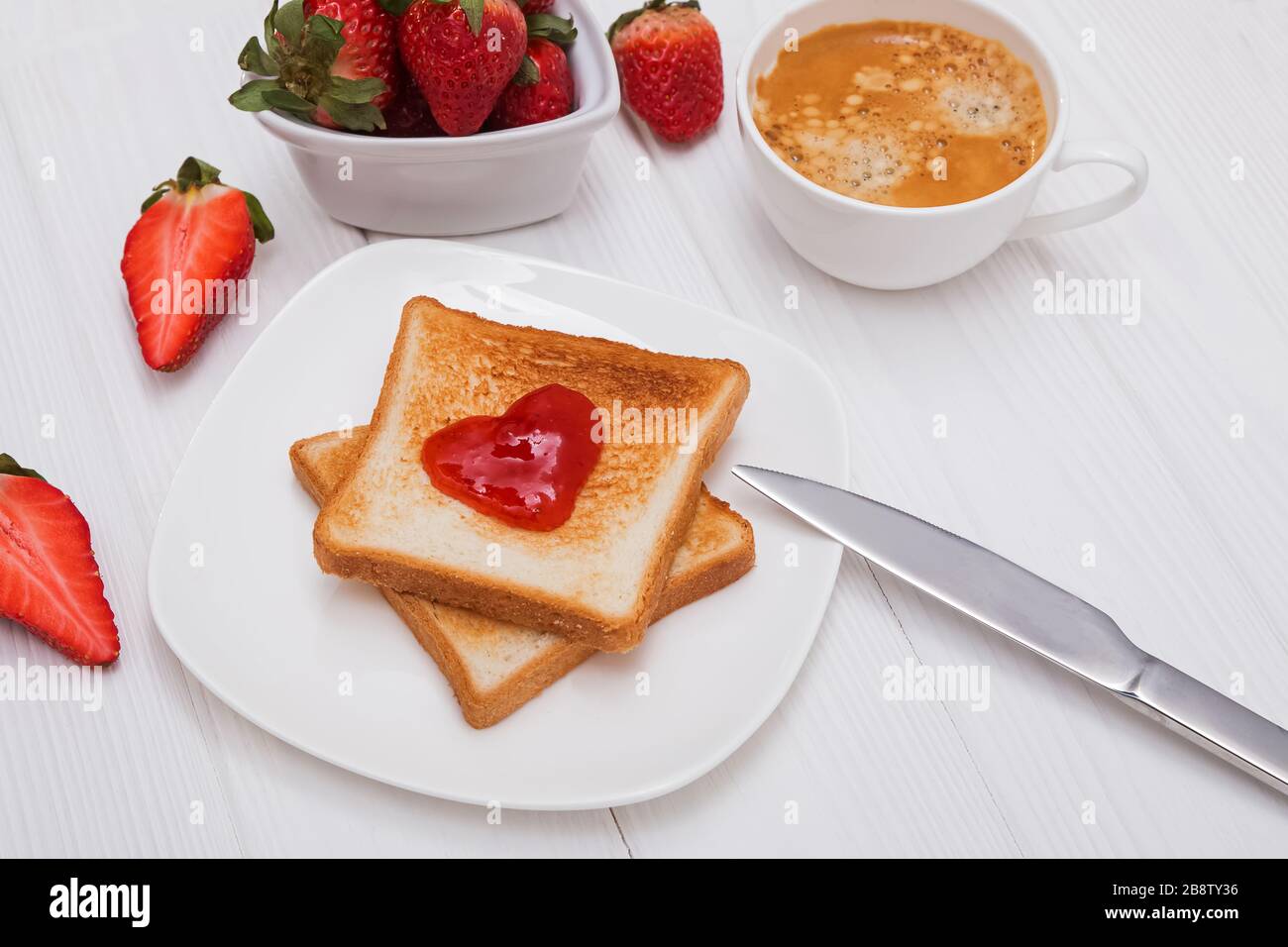 Toasts frais avec confiture de fraises en forme de coeur, café et fraises Banque D'Images