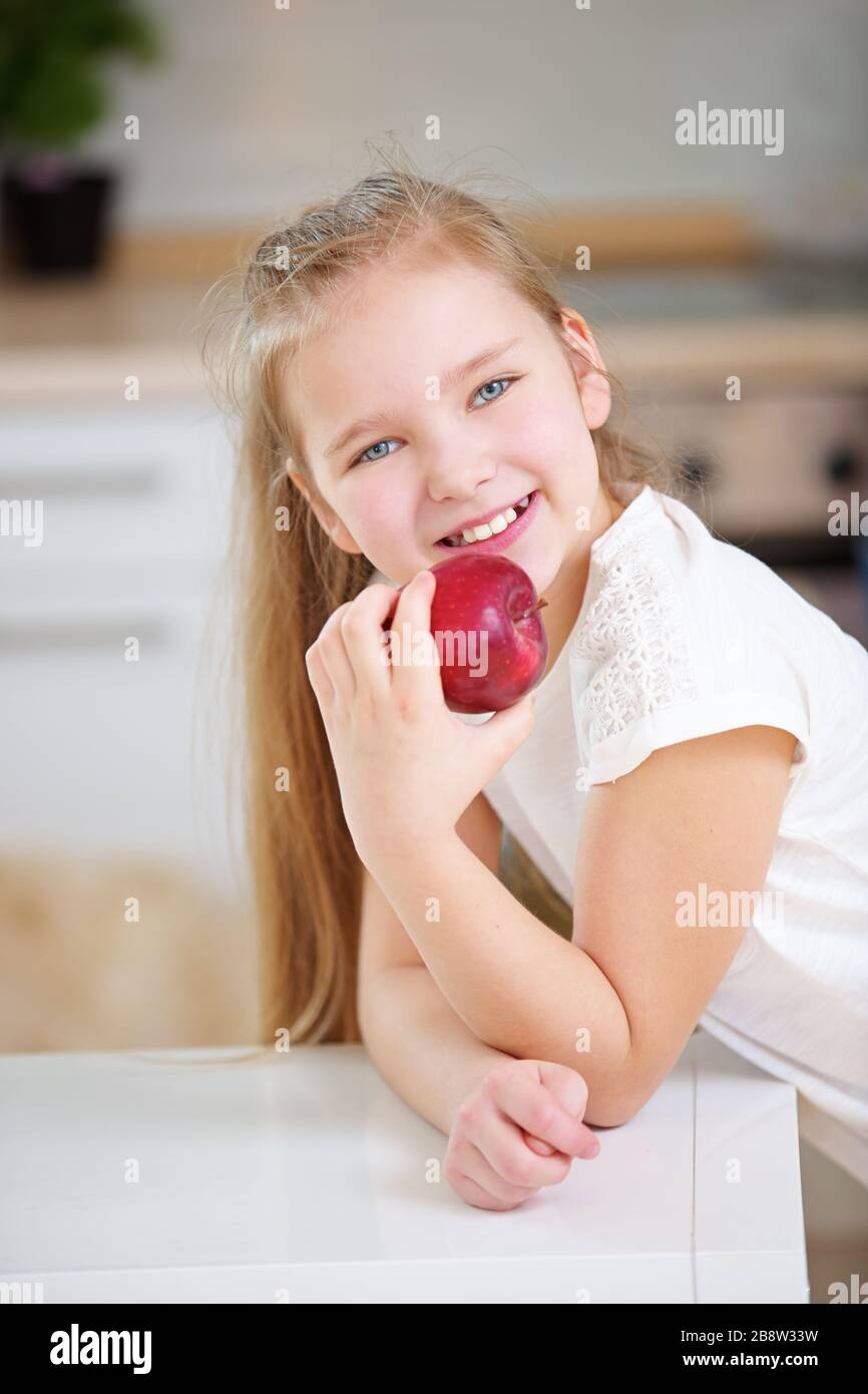L'enfant avec des dents saines tient une pomme rouge fraîche dans sa main Banque D'Images