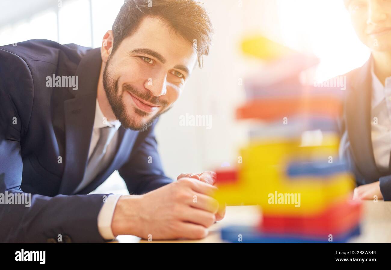 Bâtiment d'équipe dans l'atelier d'affaires avec des personnes autour d'une tour faite de blocs de construction Banque D'Images