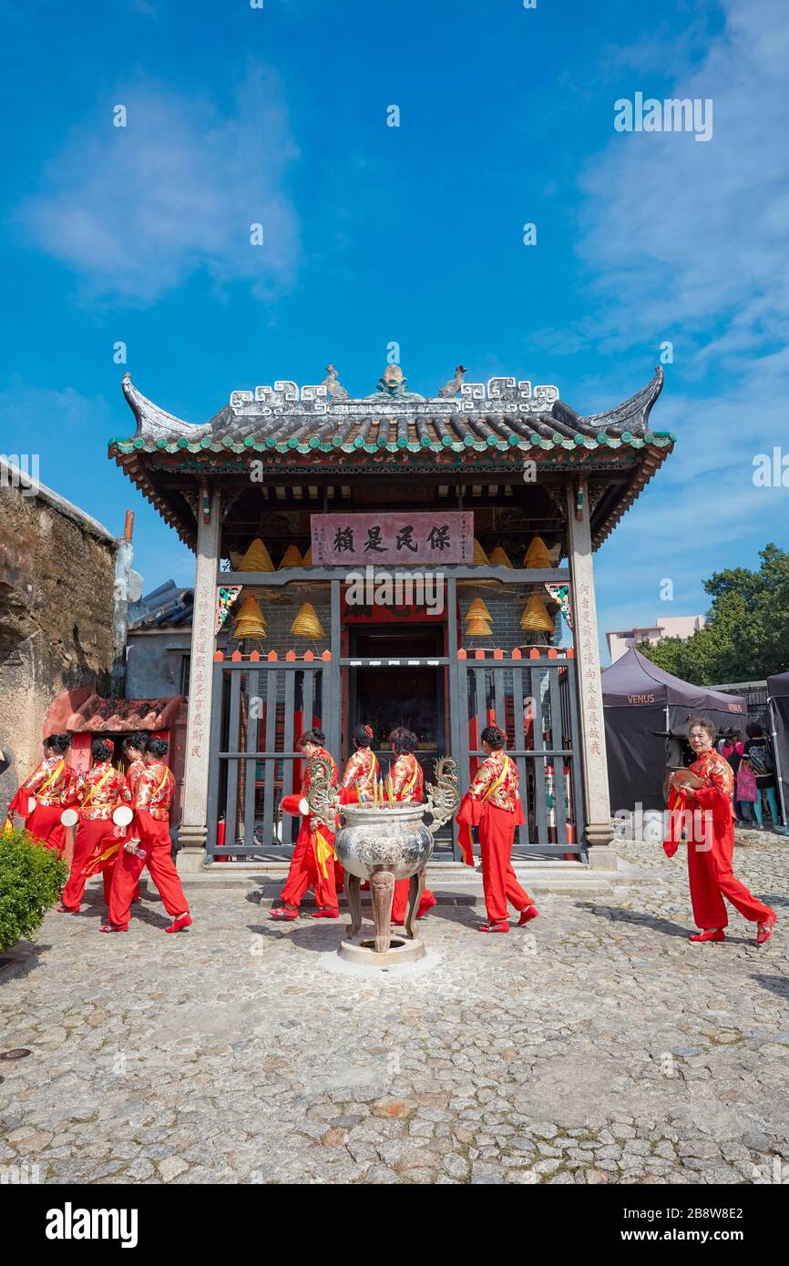 Les femmes locales en costumes traditionnels rouges marchant près du temple Na Tcha. Macao, Chine. Banque D'Images