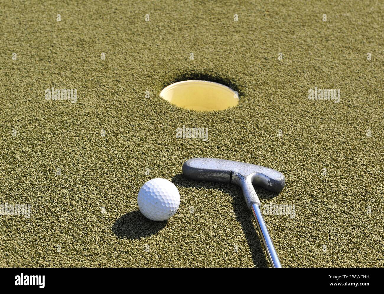 Mini-bâton de golf et balle au trou sur l'herbe Banque D'Images