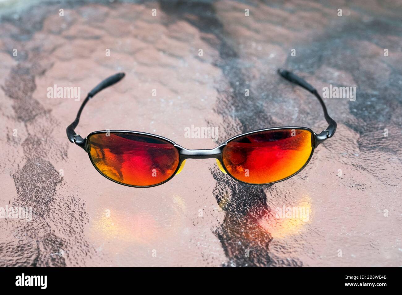 Une paire de lunettes de soleil en fil Oakley E avec des verres rouges rubis. Banque D'Images