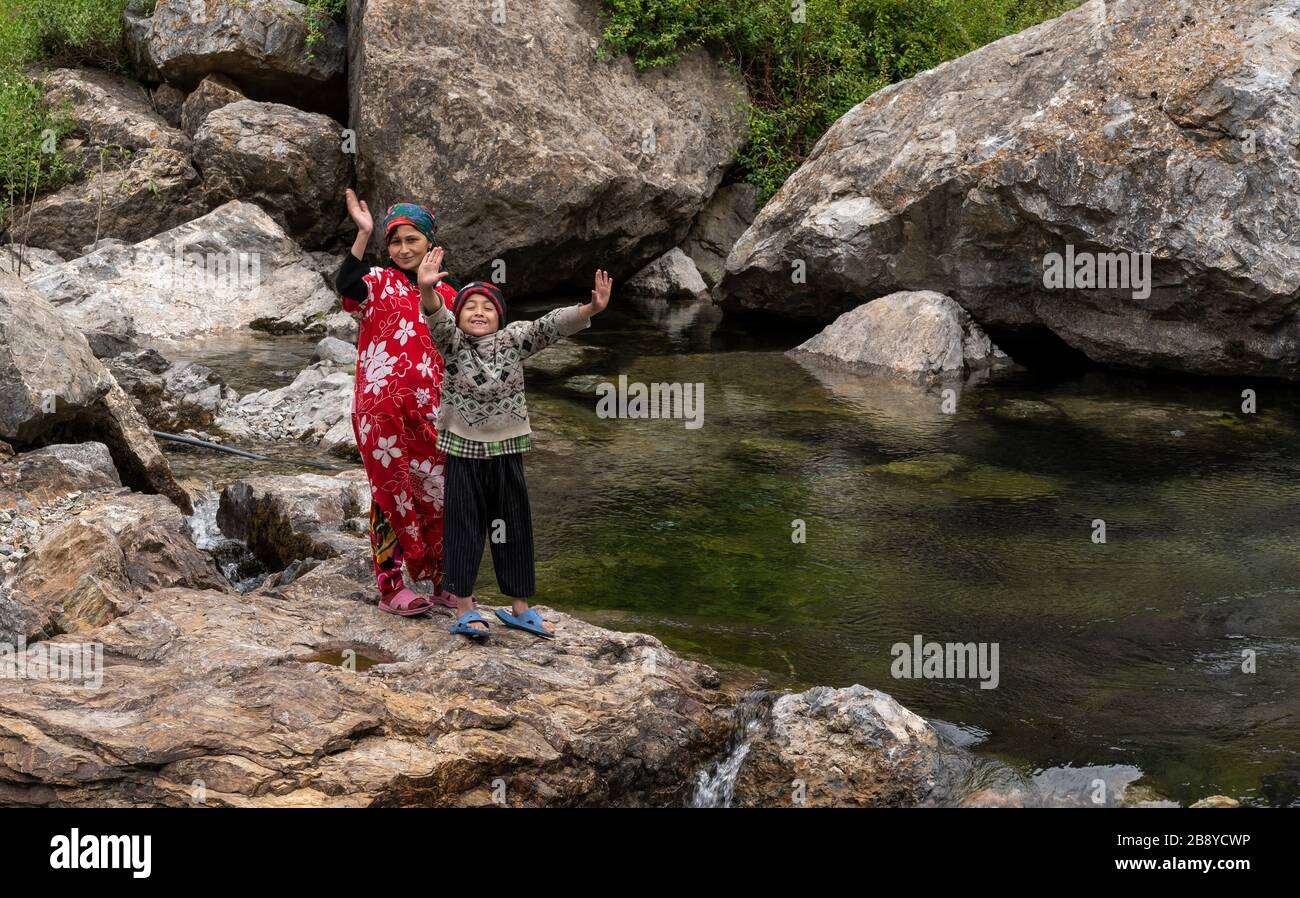 Panjakent, Tadjikistan - 10 juin 2019: Petite rivière sauvage avec deux personnes en agacement, un enfant et une femme, avec des arbres verts près des sept lacs de Tadzji Banque D'Images