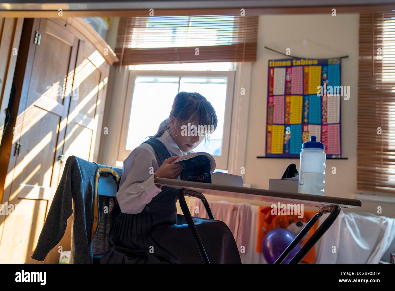 Emily, 9 ans, est assise à son bureau à la maison le premier jour de la scolarité à la maison après que les écoles ont fermé vendredi à cause de la pandémie de coronavirus. Banque D'Images