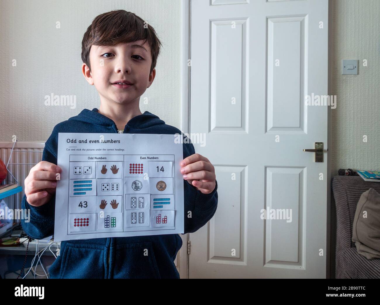 Un jeune enfant montre fièrement l'exercice de chiffres qu'il a terminé le premier jour de l'éducation à la maison en raison de la pandémie de coronavirus Banque D'Images