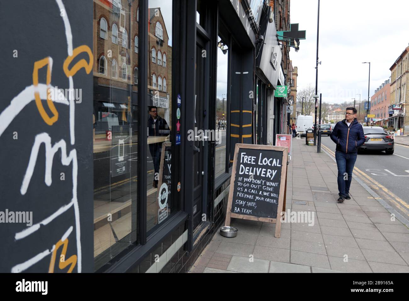 Londres / Royaume-Uni – 20 mars 2020 : un homme passe devant Bottle Apostle hors licence à Crouch End, dans le nord de Londres, qui offre une livraison gratuite dans le cadre de la pandémie de coronavirus Banque D'Images
