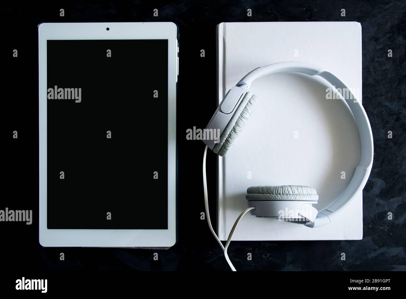 Livre de papier, ebook et format de livre audio sur une table en bois noir. Vue du haut vers le bas d'un bureau avec espace de copie vide pour le contenu de l'éditeur. Banque D'Images