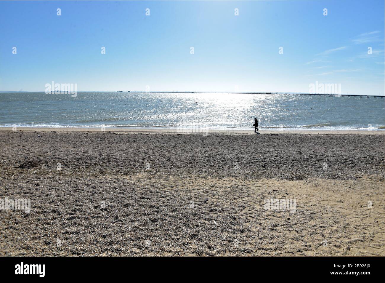 Une figure solitaire marche le long du rivage sur une plage vide à Southend, dans l'Essex, comme le Premier ministre Boris Johnson l'a dit, le gouvernement est prêt à imposer des restrictions plus sévères pour freiner la propagation du coronavirus si les gens ne suivent pas les directives sur la distanciation sociale. Banque D'Images