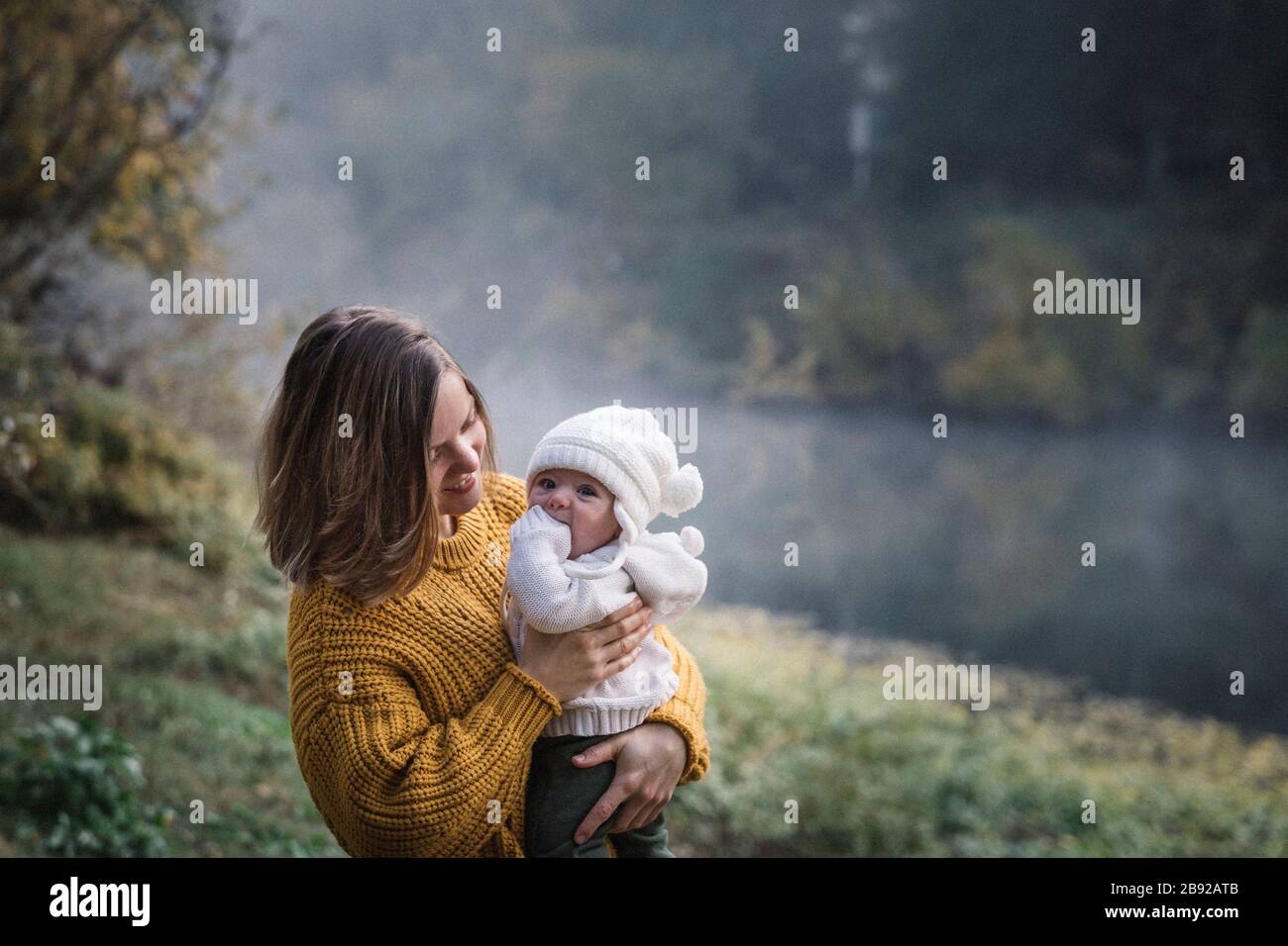 Une femme tient un bébé près d'une rivière Banque D'Images