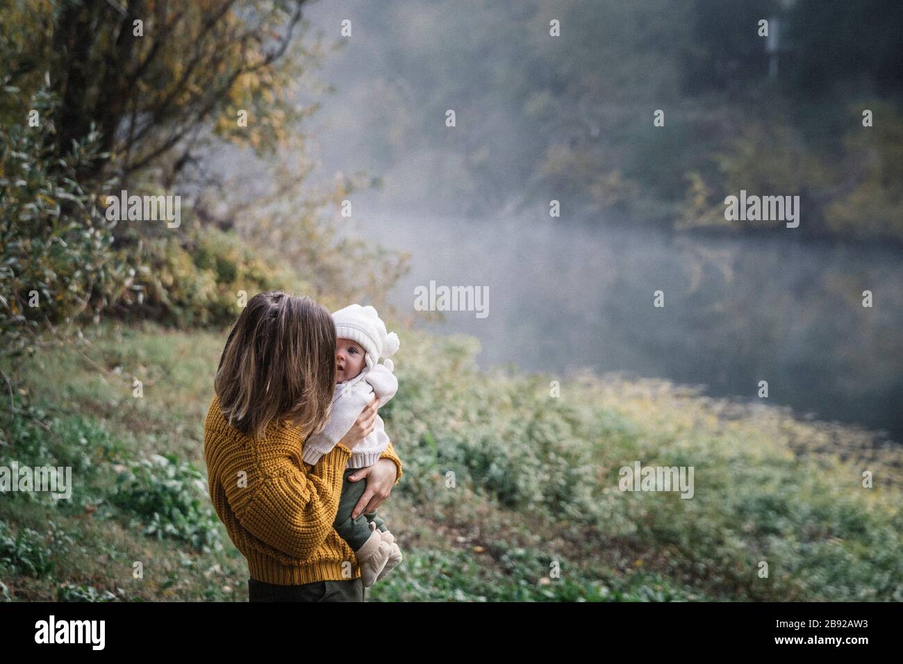 Une femme tient un bébé près d'une rivière Banque D'Images
