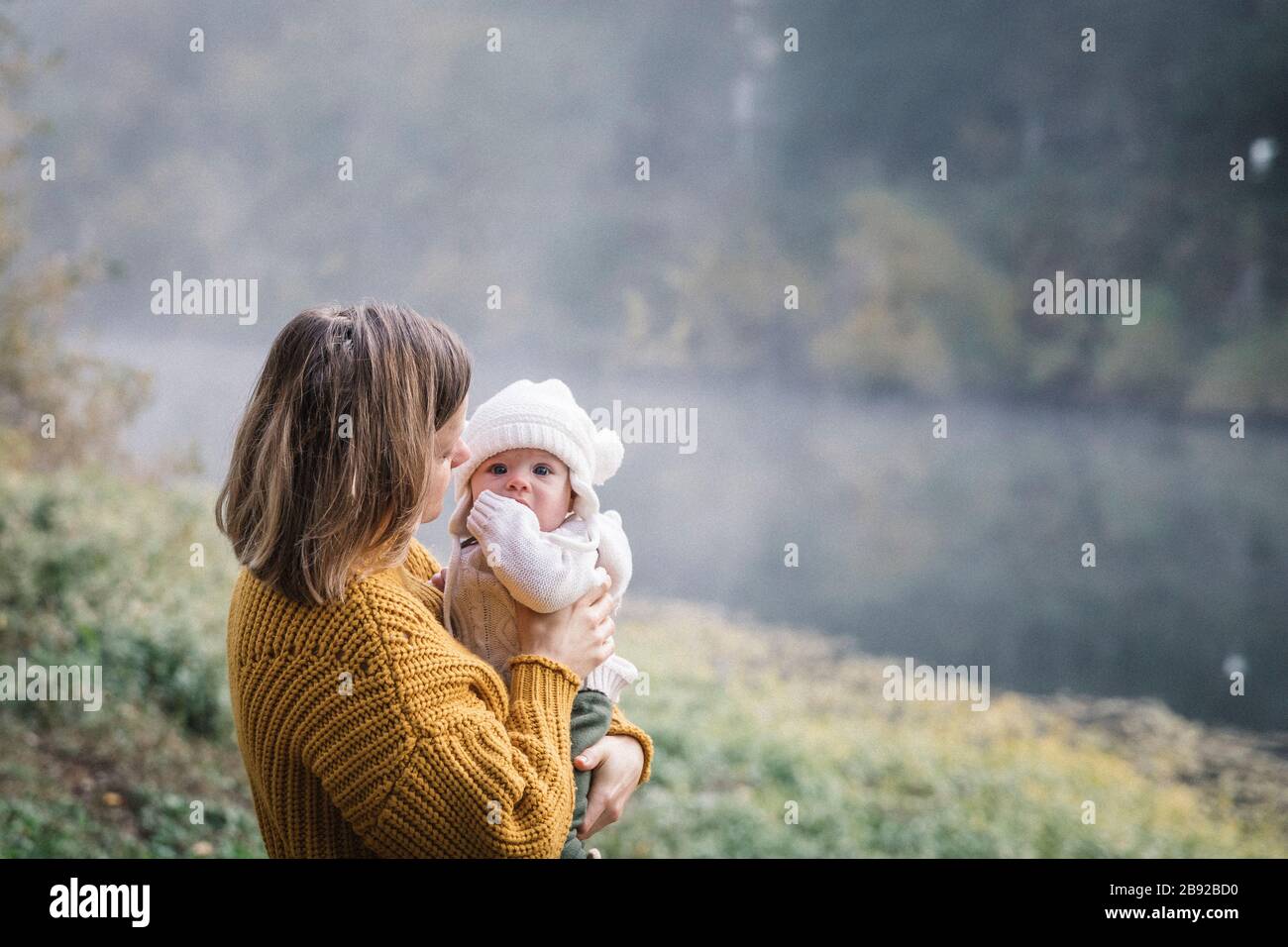 Une femme tient un bébé près d'une rivière Banque D'Images