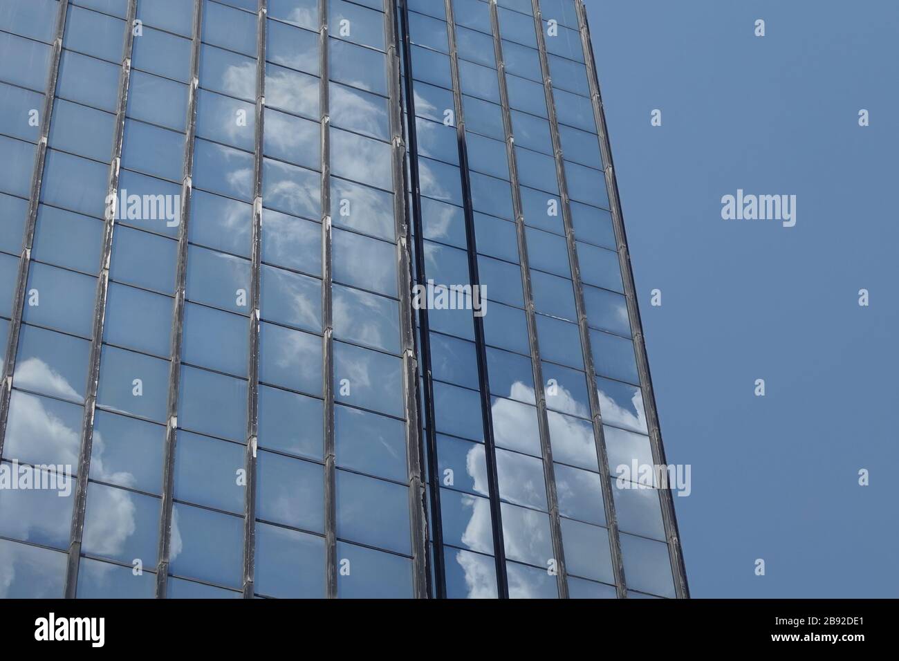 Nuages et ciel bleu réfléchis sur des fenêtres de bâtiment en verre. Contexte architectural. Banque D'Images