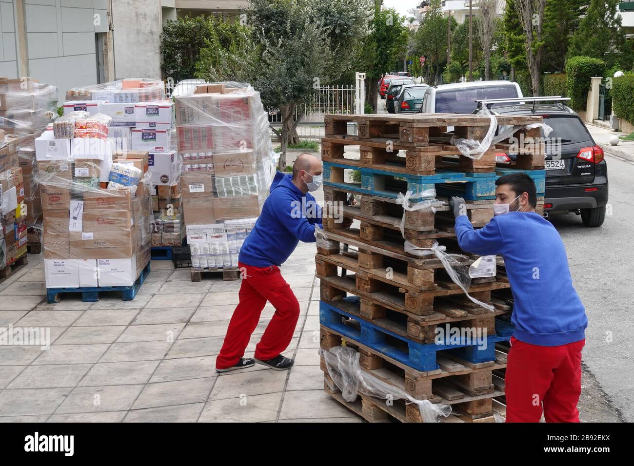 Athènes, Grèce - 16 mars 2020: Les employés des supermarchés portant des masques protecteurs déchargent des palettes avec des aliments emballés pendant le covid-19 du coronavirus Banque D'Images