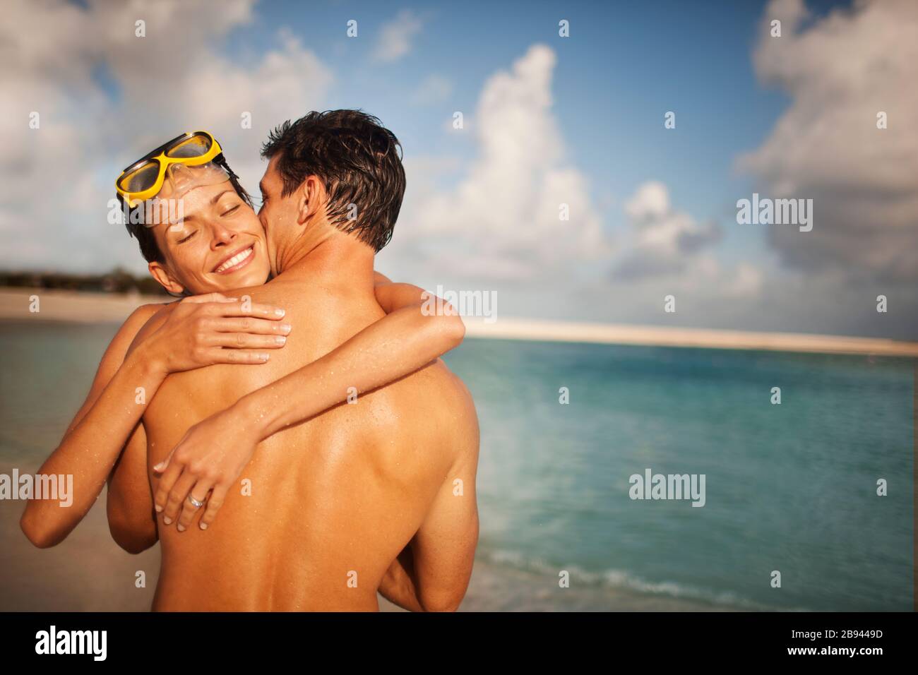Smiling mid-adult woman d'être embrassé sur la joue de son mari sur une plage. Banque D'Images