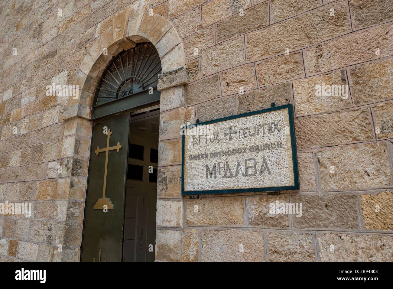 La magnifique plaque en mosaïque à l'entrée de l'église orthodoxe grecque de Saint George à Madaba, Jordanie. Vue sur la rue de la journée d'hiver avec la vieille porte ouverte du bâtiment religieux Banque D'Images