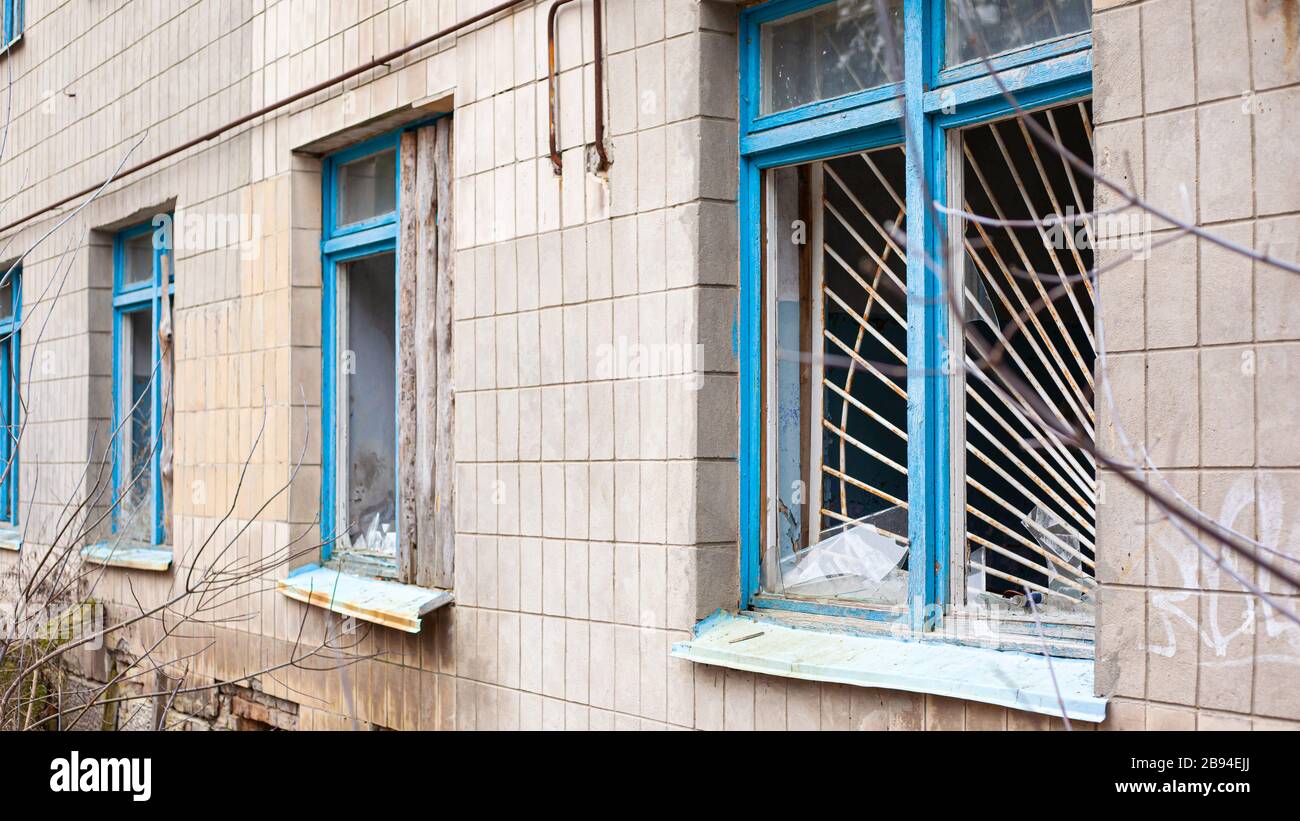 vieilles fenêtres cassées avec barres métalliques d'un bâtiment hospitalier abandonné. Banque D'Images