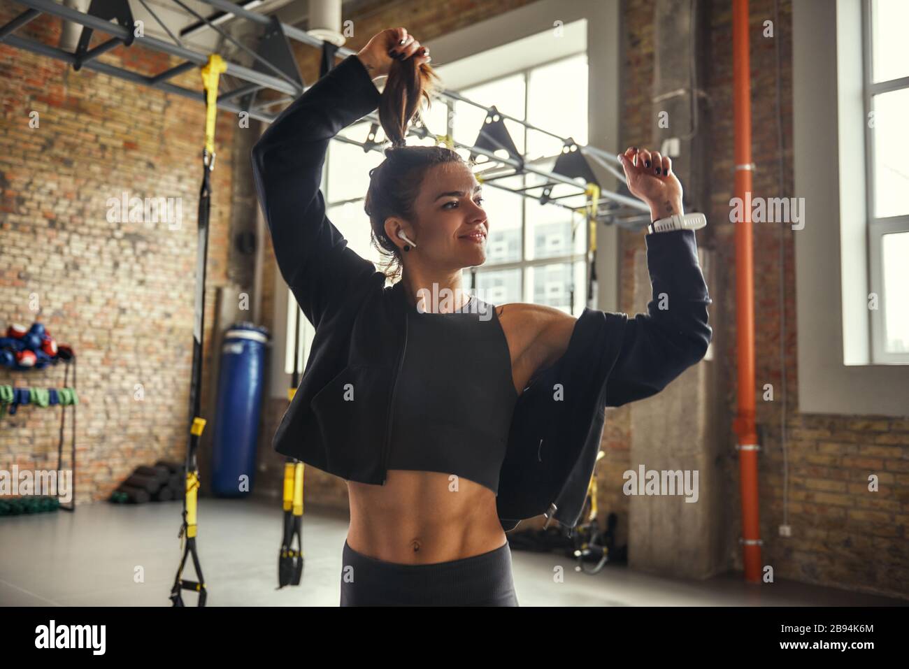 Se sentir heureuse positive et attrayante jeune femme dans un casque écoutant de la musique et souriant tout en faisant de l'exercice à la salle de gym. Le bonheur. Concept sportif. Motivation Banque D'Images