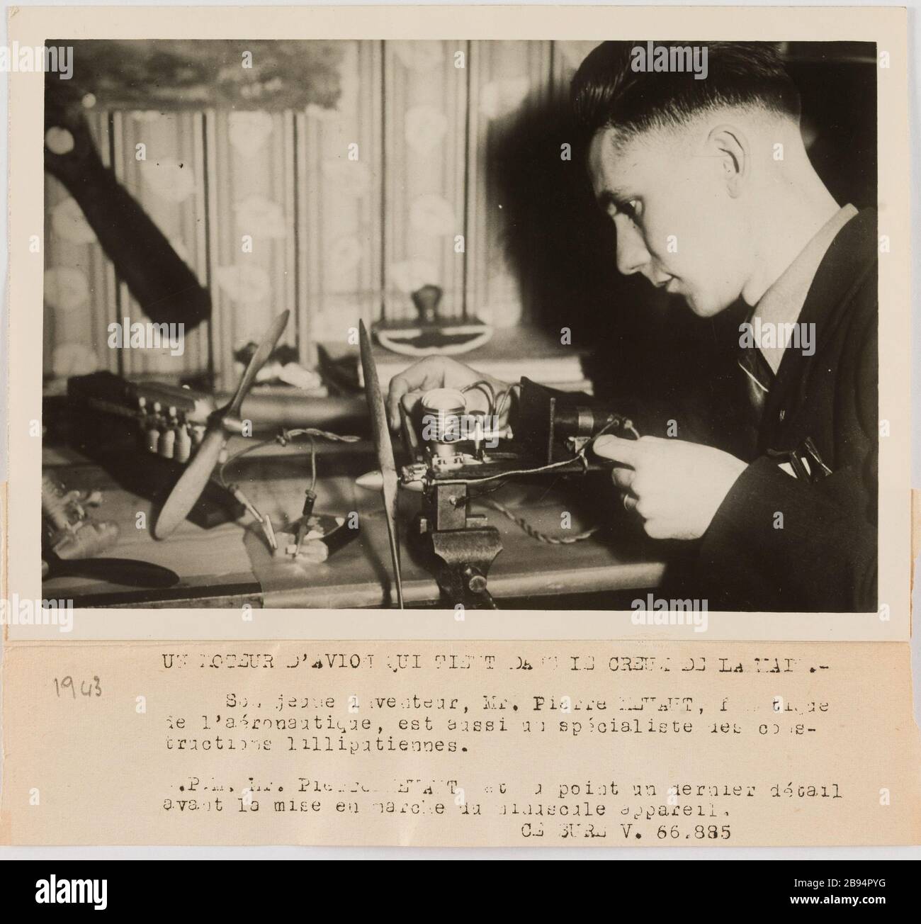 Photographie propagande jeune homme travaillant sur un modèle de moteur d'avion. Agence LAPI (les Actualités photographiques internationales). 'Photo propagande : jeune homme trayant sur un moteur d'avion miniature'. UN MOTEUR D'AVION QUI TIENT DANS LE CREUX DE LA MAIN. / son jeune inventeur, M. Pierre (...) / de l'aéronautique, est aussi un specialiste des contre- / tructions liputiennes. / N.P.M. M. Pierre (...) point un dernier queue / avant la mise en marche du minuscule appareil. Rage au gélatino-bromure d'argent. Légende dactylographiée à l'encre Noire. En 1943-02-24-1943-02-24. PA Banque D'Images