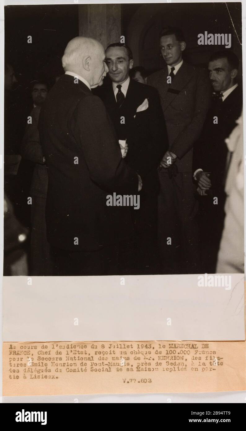 Propagande photographique le maréchal Pétain parle avec Henrion Service central photographique (SCP). 'Photographie propagande : le Maréchal Pétain s'entretien avec M. Henrion'. Au cours de l'audience du 8 juillet 1943, le MARECHAL DE / FRANCE, Chef de l'Etat, reçoit un chèque de 100.000 Francs / pour le secours National des mains de M. HENRION, des fila- / tures Emile Henrion de Pont-Mangis, près de Sedan, À la tête / des éléments du Comité social de sa Maison remplie par- / tie à Lisieux. / V.77.802. Rage au gélatino-bromure d'argent. Légende dactylographiée à l'encre Noire. En 1943-07-09-1 Banque D'Images